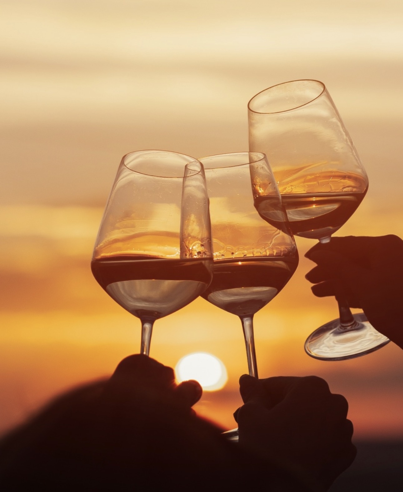 Três copos de vinho a brindar ao pôr do sol no Algarve.
